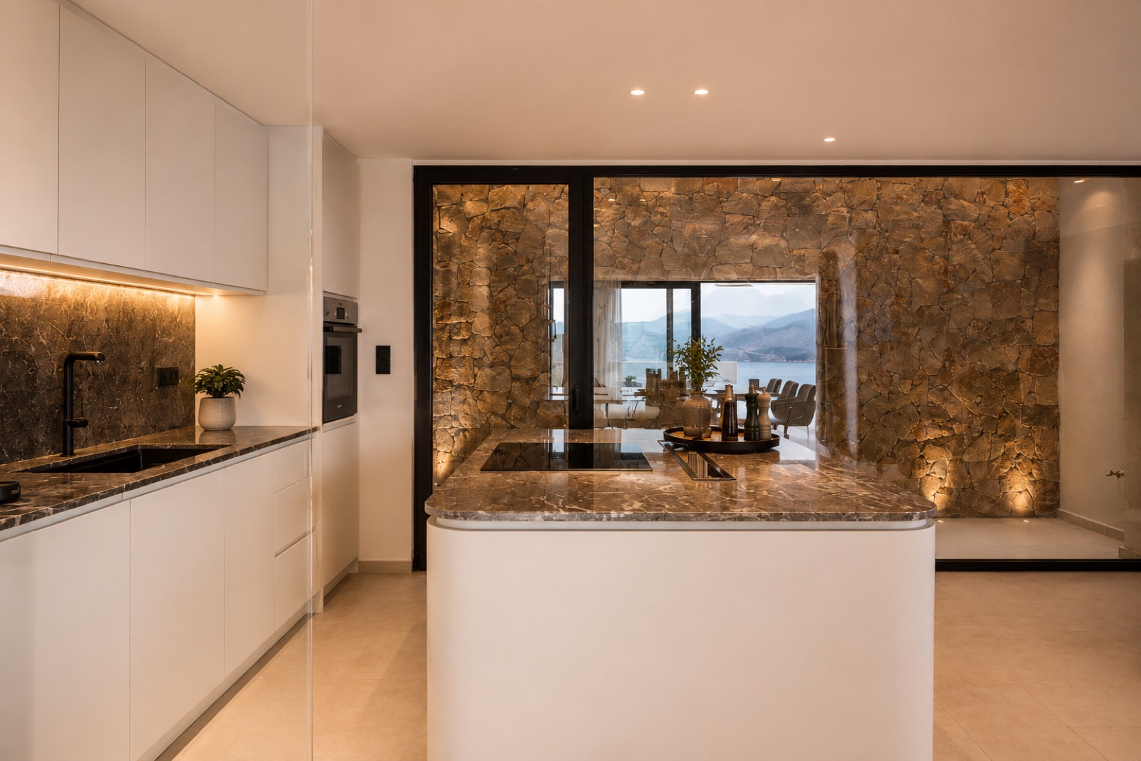 White kitchen with stone wall and sea view